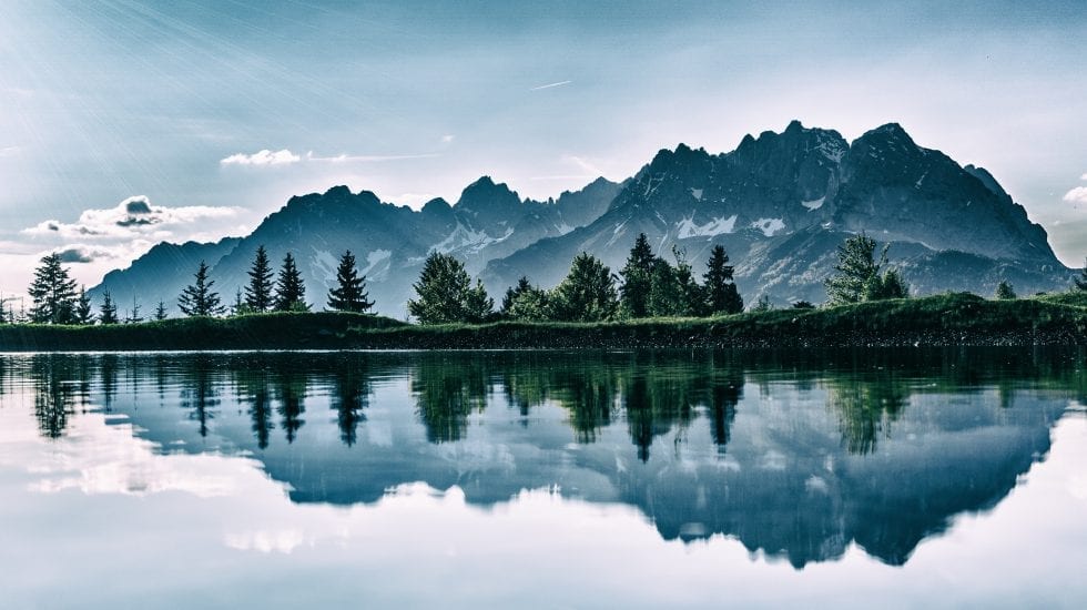 Paisaje de montañas y su reflejo en un lago creando simetría horizontal. Compra pública de innovación
