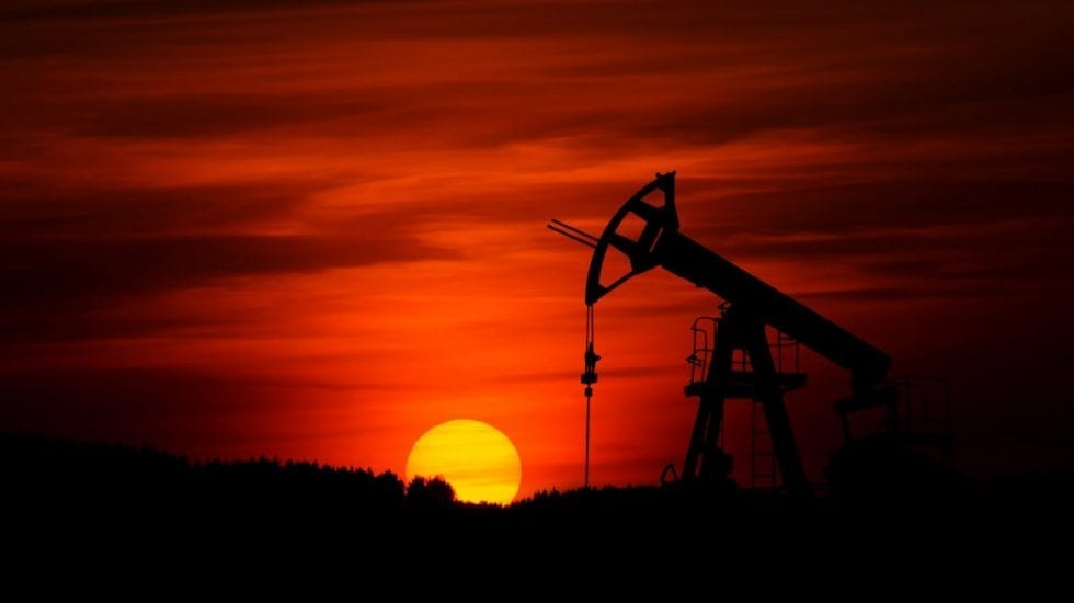 atardecer con la silueta de una bomba en una explotación petrolífera. Mercado energético.